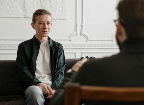 A teenager sits across from a counselor in a therapy session, promoting mental health awareness.