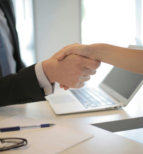 Close-up of a professional handshake over a laptop during a business meeting in an office.